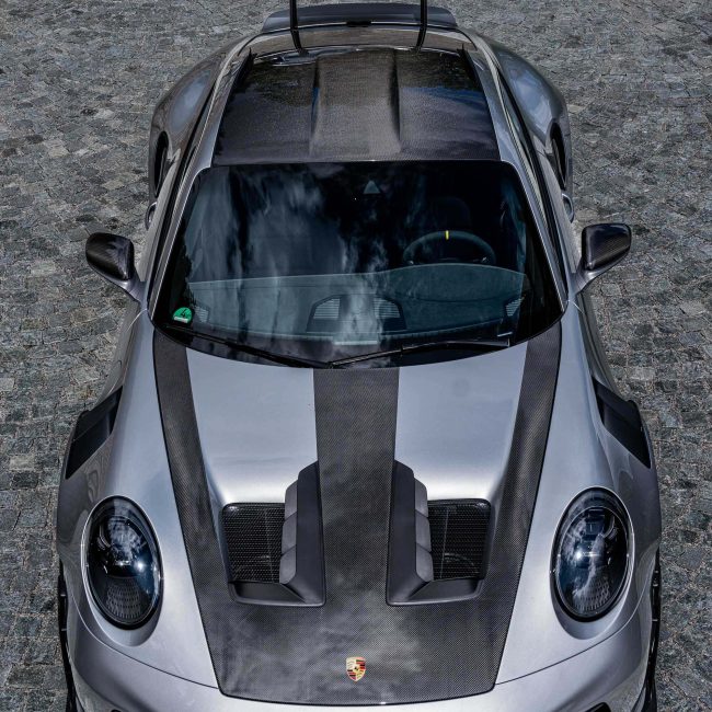 Silver Porsche Sports Car with Carbon Elements and Large Rear Spoiler on Cobblestones