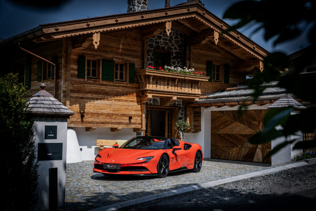 Roter Sportwagen vor Chalet mit Holzbalkon