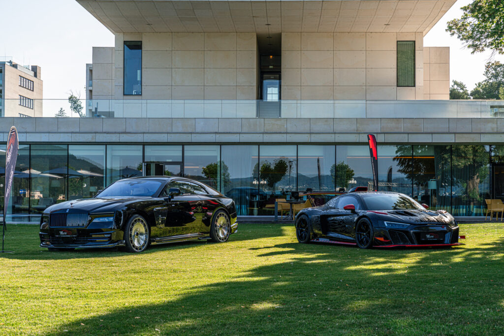 Zwei schwarze Luxus-Sportwagen vor modernem Gebäude auf Rasenfläche