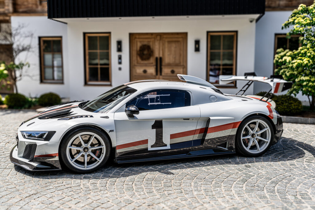 Weißer Sportwagen mit Startnummer 1 vor einem Haus